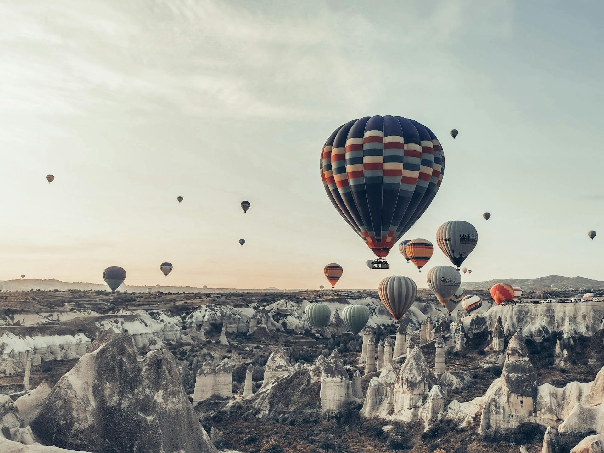 Multicolored hot air balloons flying above famous vast rocky valley in Cappadocia Turkey on early morning on fair weather
