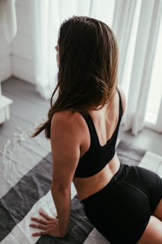 A woman performing a yoga pose indoors, emphasizing a healthy lifestyle and flexibility.