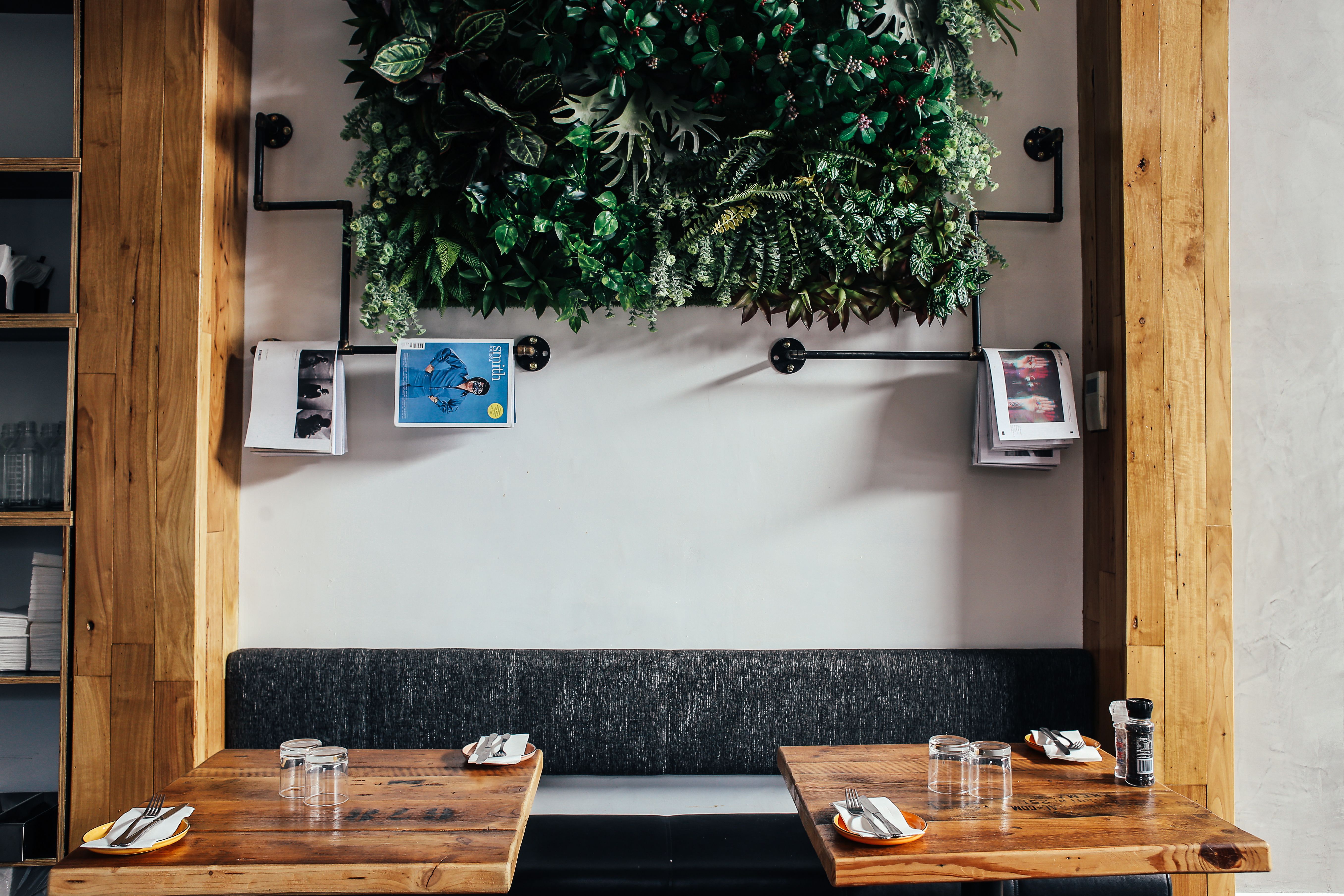 Contemporary cafe interior featuring a wooden table, bench seating, and a lush vertical garden.