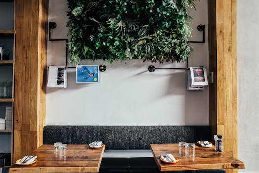 Contemporary cafe interior featuring a wooden table, bench seating, and a lush vertical garden.
