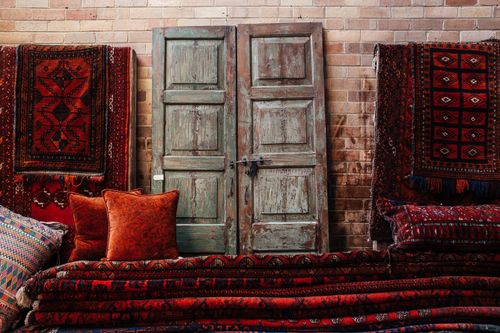 Free Vintage wooden door surrounded by vibrant, patterned rugs and pillows, creating a warm, rustic ambiance. Stock Photo