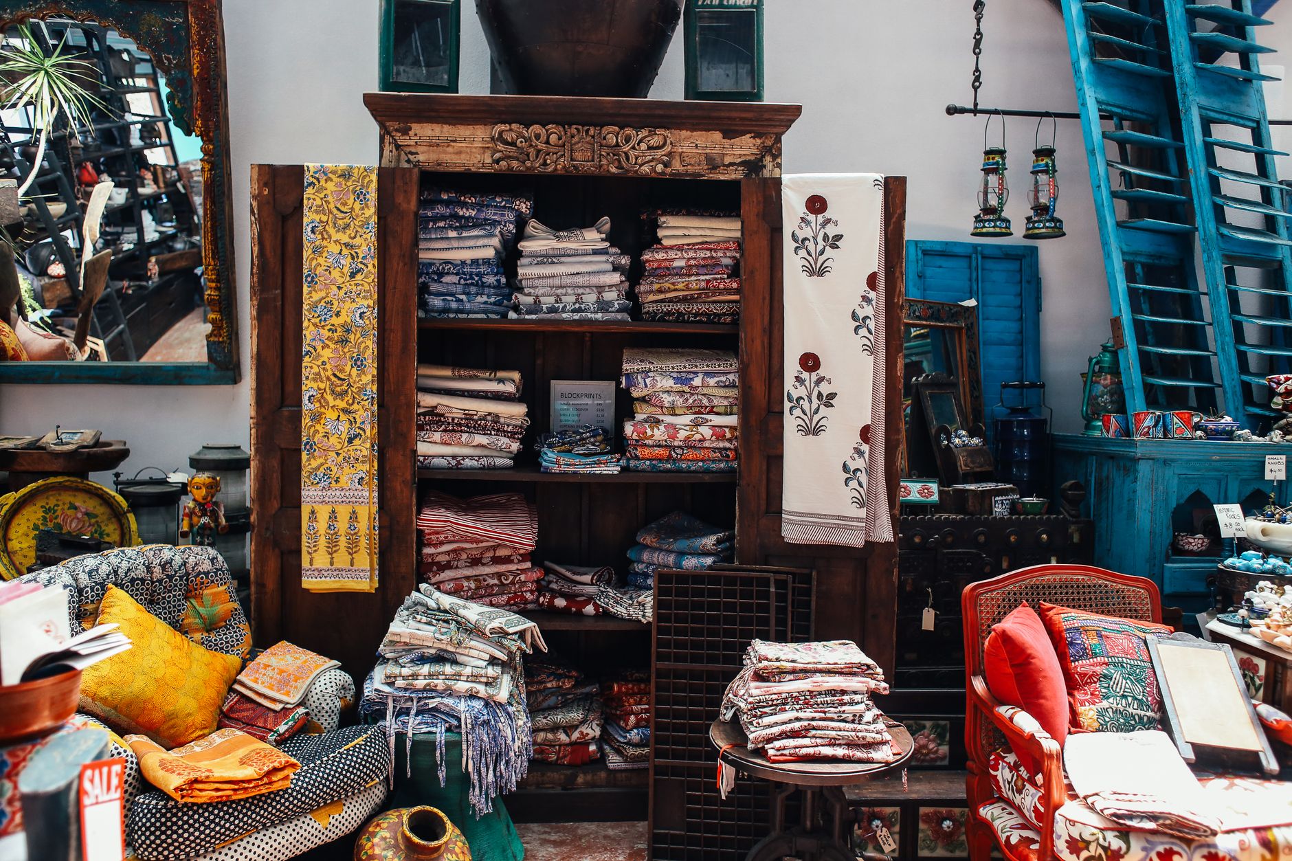 best home decor stores budget shopping guide An intricate display of colorful textiles and home decor in a vintage store interior setting.