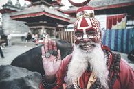 Cheerful Nepalese man in authentic costume demonstrating coins on palm