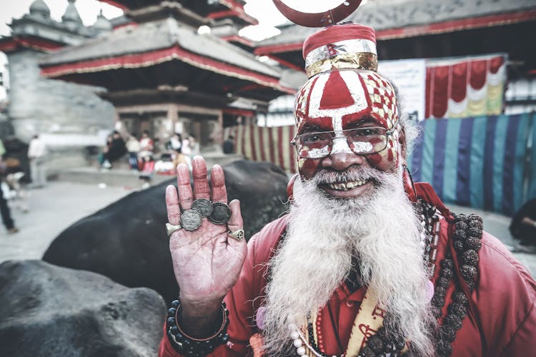 Cheerful Nepalese Man In Authentic Costume Demonstrating Coins On Palm