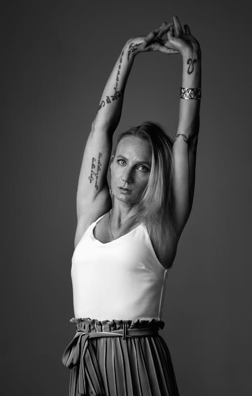 Woman in White Tank Top Raising Her Arms Up