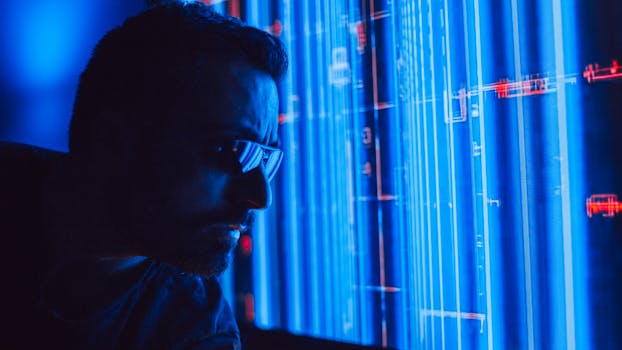 A man in sunglasses intently studies a vibrant blue holographic screen, symbolizing digital technology.