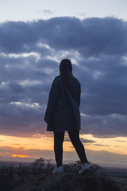 Person Standing on Rock Under Cloudy Sky
