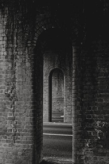 Grayscale photo of brick arches in a tunnel creating a moody, timeless atmosphere.