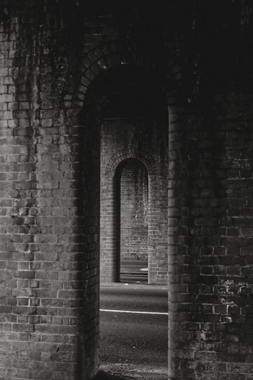 Grayscale Photo of Brick Tunnel