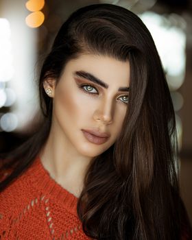 Elegant portrait of a young woman with brown hair in a warm indoor setting.