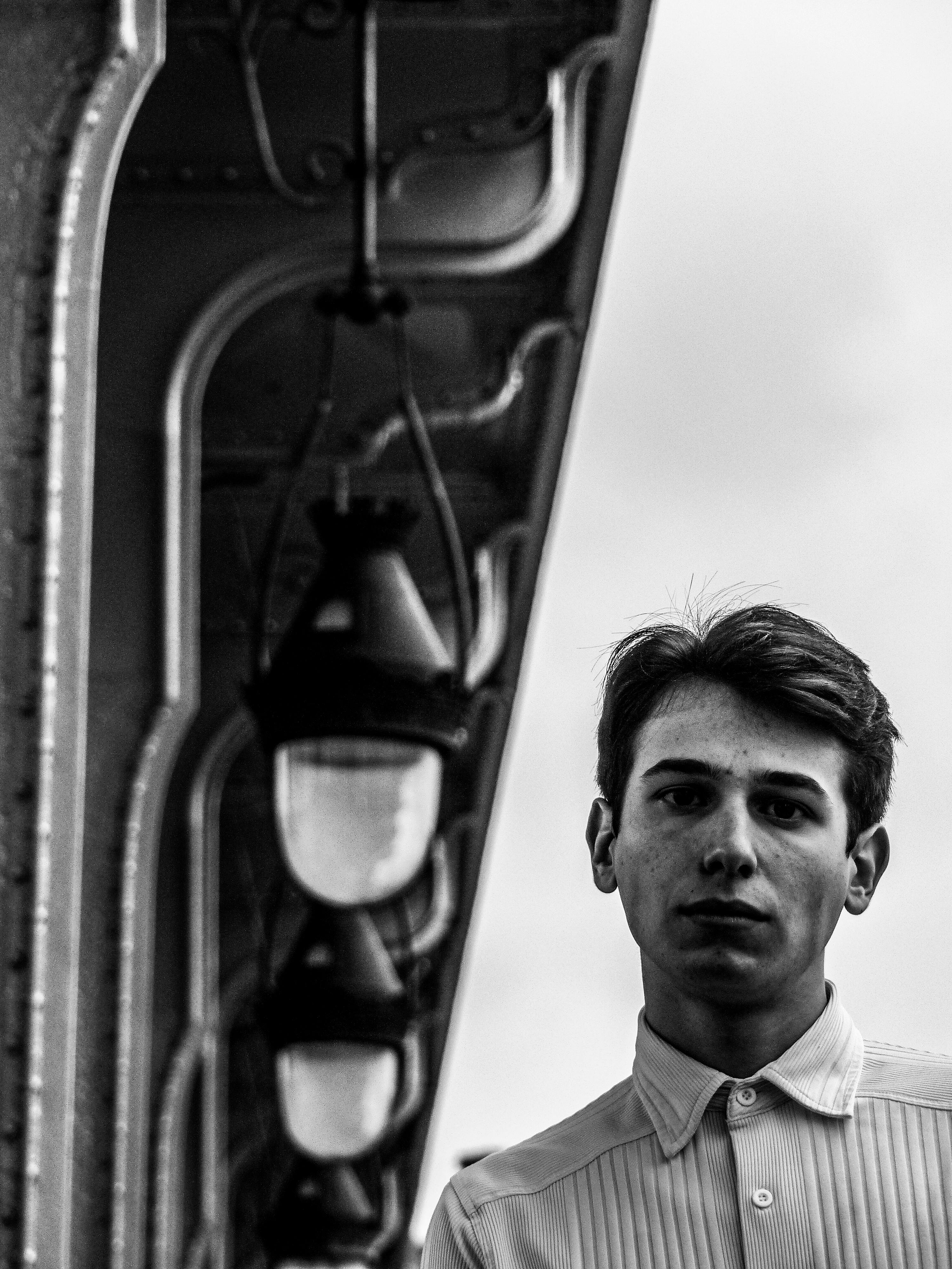 Striking black and white portrait of a young man beneath a Parisian bridge.