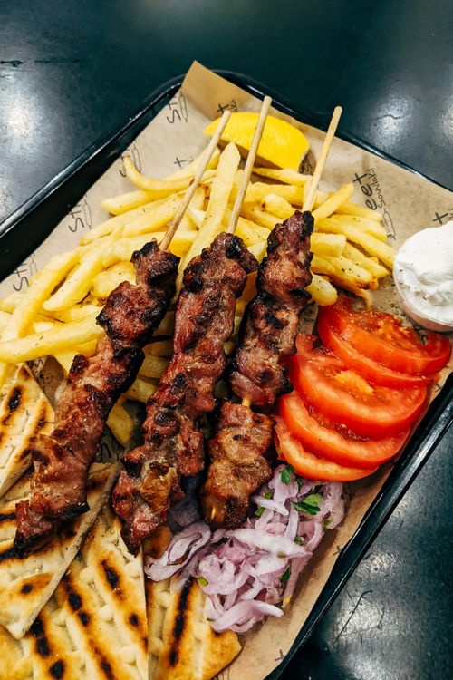 Free A mouth-watering dish of grilled skewers, fries, and fresh veggies, perfect for a tasty meal. Stock Photo