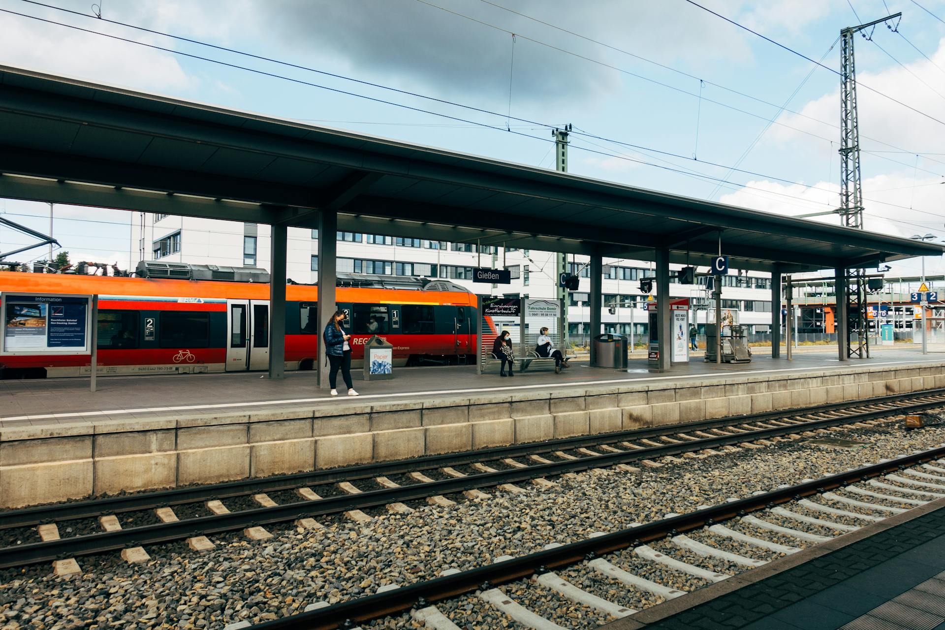 View of Giessen train station platform with commuters and a regional train in Germany.