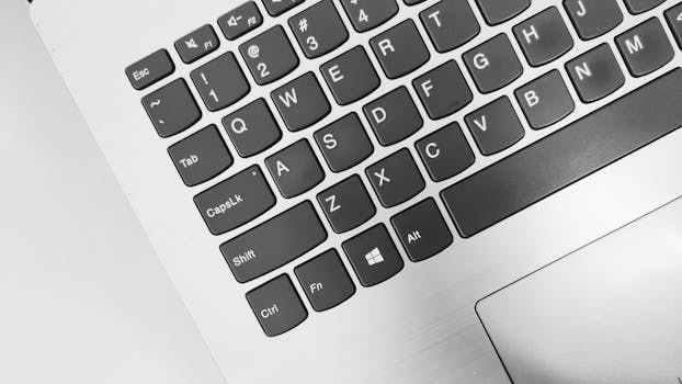 Monochrome close-up of a laptop keyboard showing keys and letters.