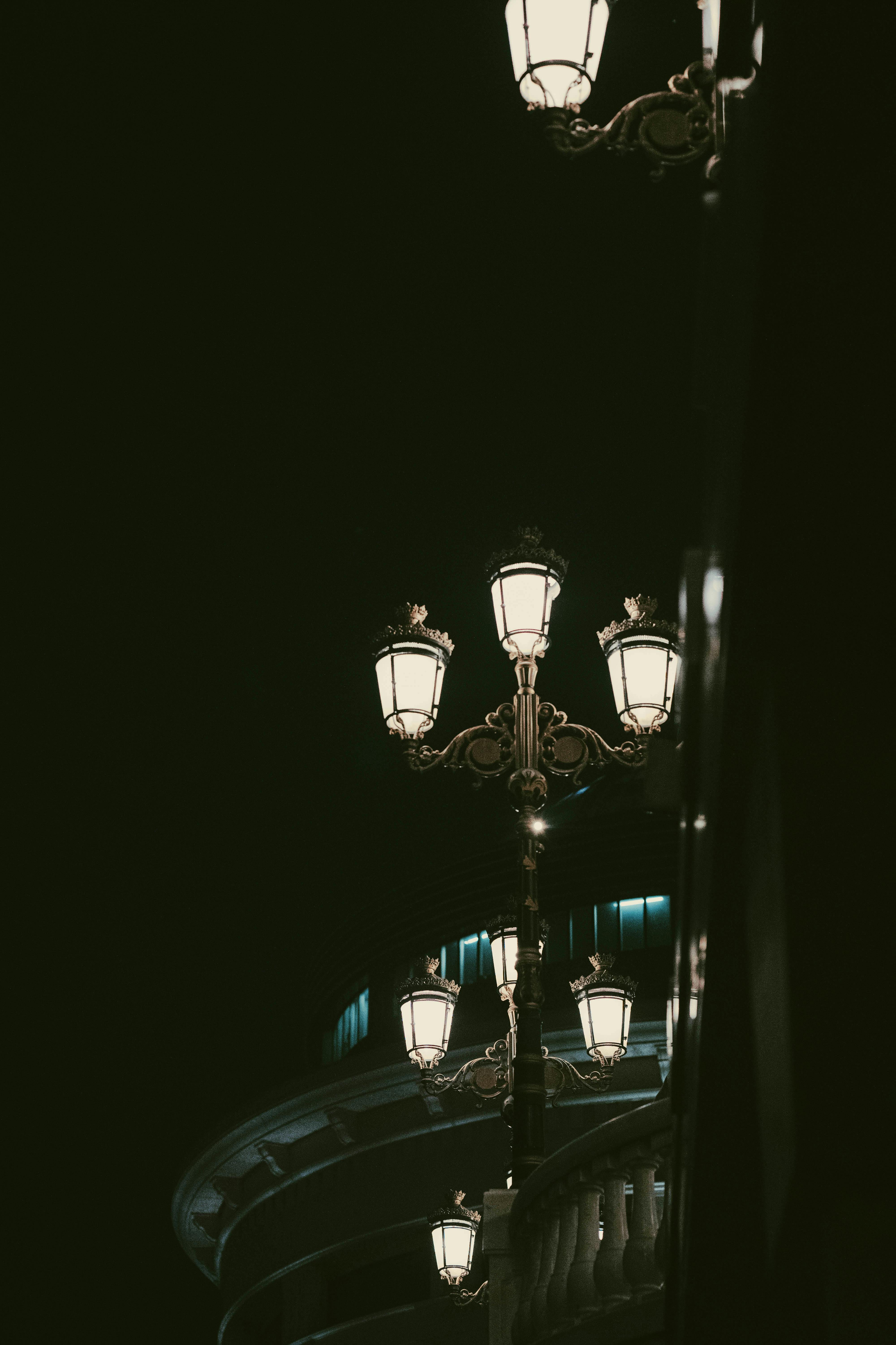 Aesthetic view of vintage street lamps illuminating the night with elegant architecture in the background.