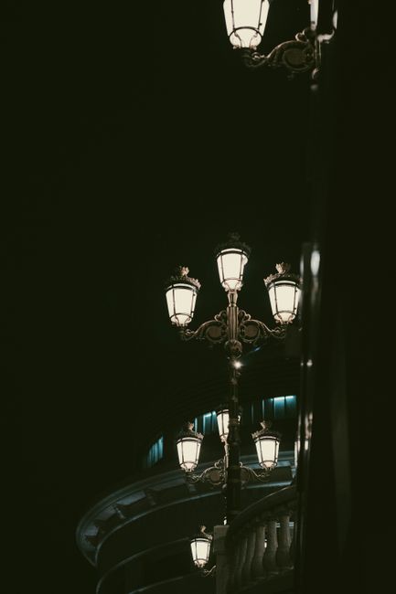 Aesthetic view of vintage street lamps illuminating the night with elegant architecture in the background.