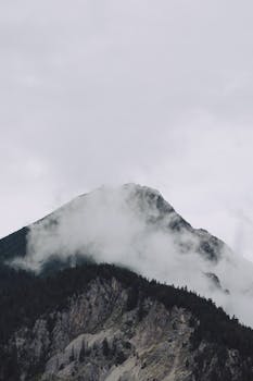 A dramatic view of a mist-covered mountain peak in Kochel am See, Germany, showcasing natural beauty.