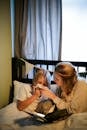 Woman in Beige Shirt Sitting on Bed Beside Woman in White Shirt