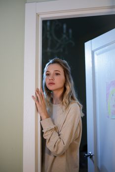 一位金发年轻女子若有所思地站在门口