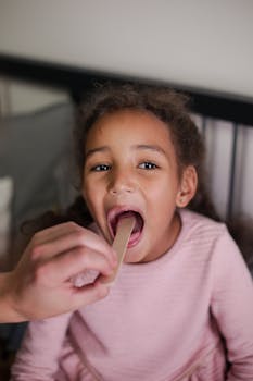 A young girl having her throat examined during a home medical checkup.