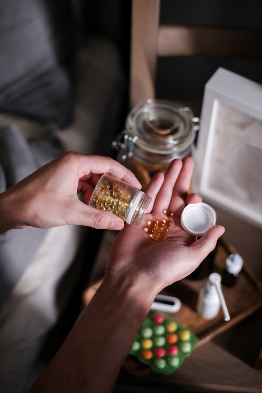 Hand pouring capsules from a supplement bottle into a palm.