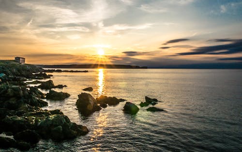 Free Rock Formations Beside Body of Water during Golden Hour Stock Photo