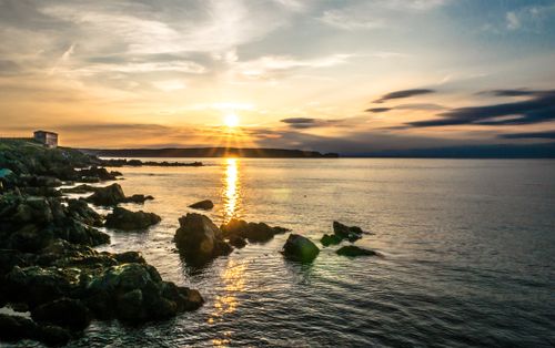 Free Breathtaking view of a sunset reflecting over a rocky coastline, highlighting the serene beauty of the sea. Stock Photo