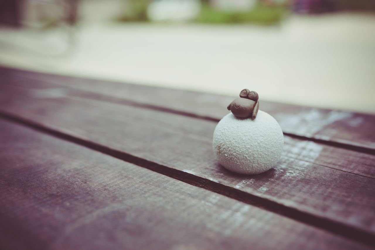 a small toy frog perched on a textured ball on a rustic wooden table o