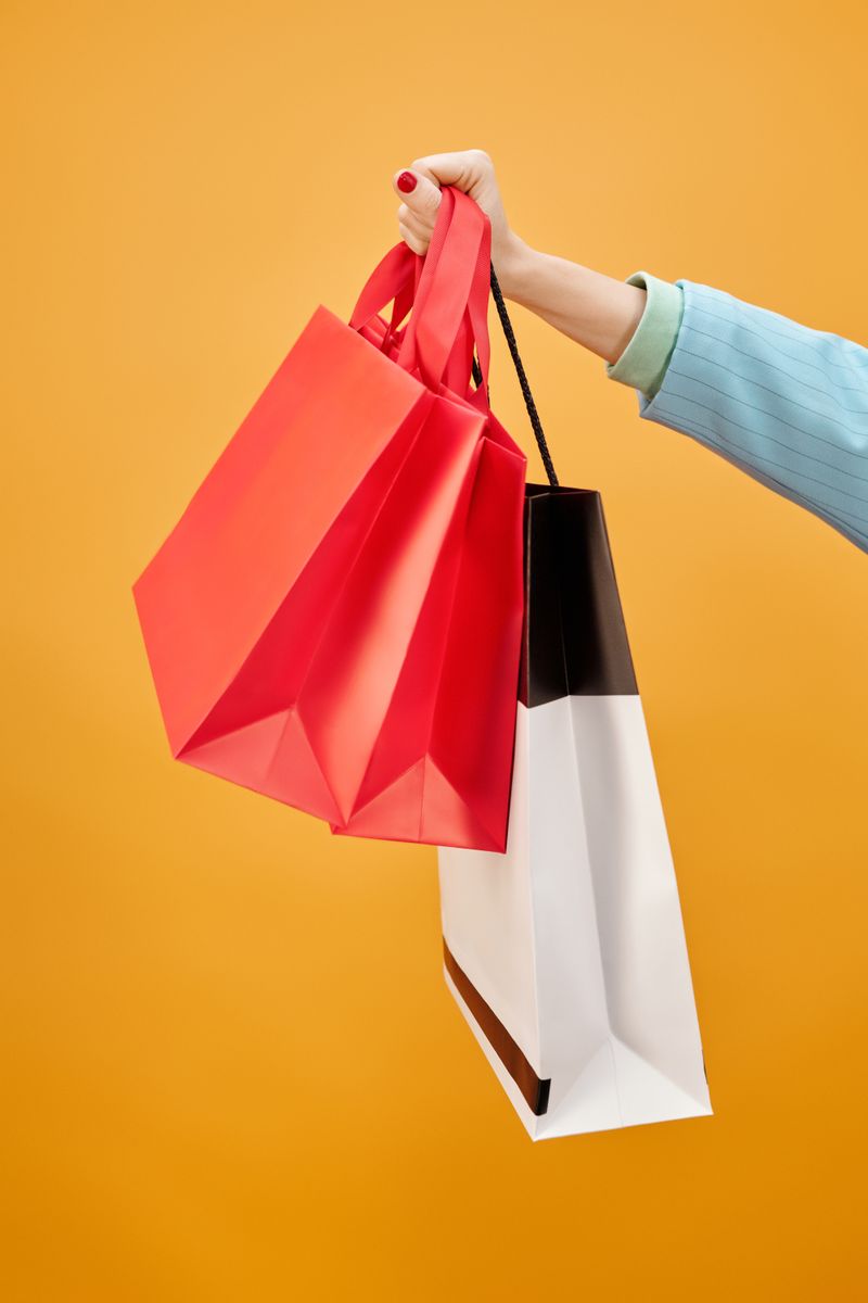 Hand holding blank paper carrier bags against a seamless colour backdrop — photo by Max Fischer on Pexels