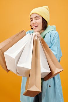 一位快乐的女士戴着无檐帽，在充满活力的背景下拿着几个购物袋