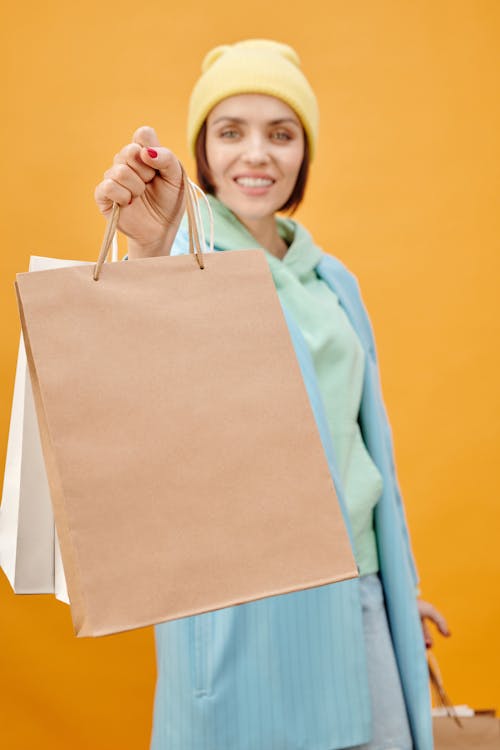 Woman in Teal Coat Showing the Paper Bags she is Holding