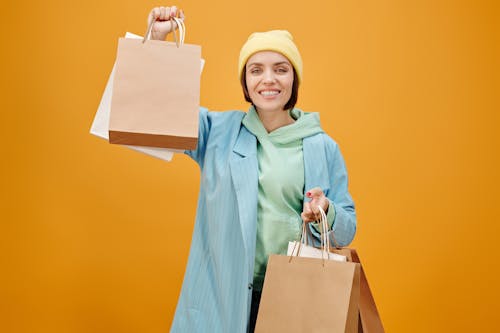 Free Woman in Teal Coat Showing the Paper Bags she is Holding Stock Photo