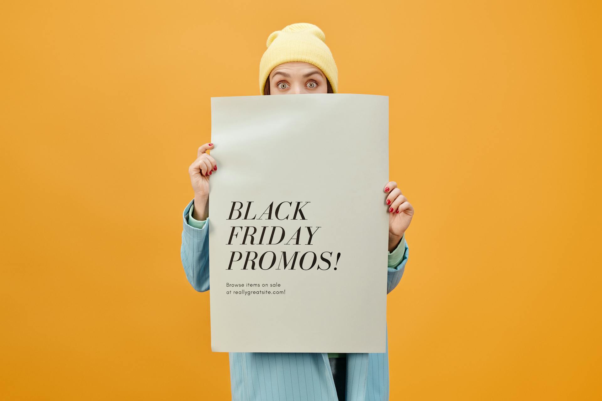 Person holding a Black Friday promo poster against a vibrant orange background. Ideal for sales and marketing concepts.