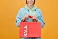 Smiling Woman in Gray Long Sleeve Shirt Holding Red Box