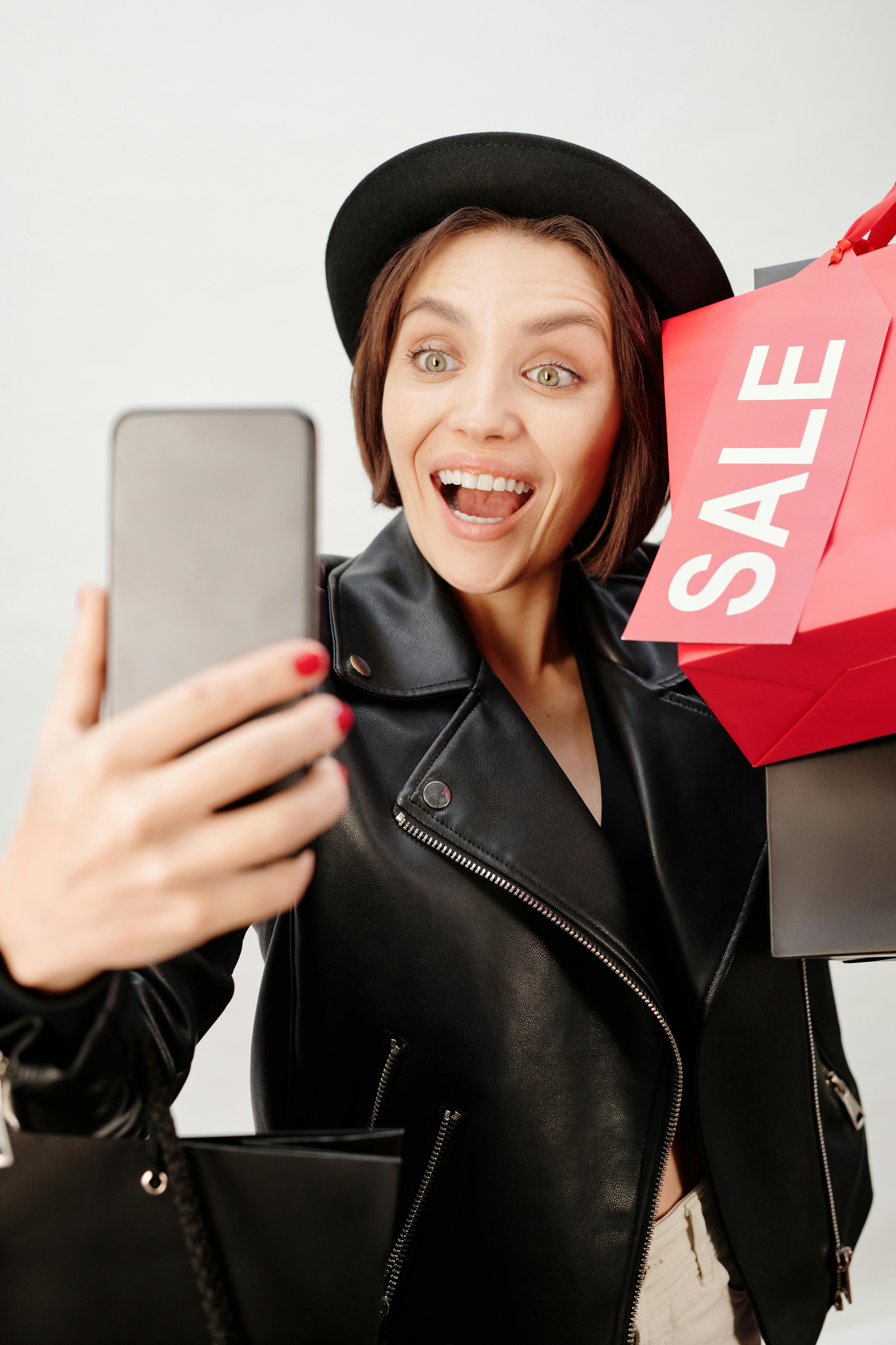 smiling woman in black leather jacket holding shopping bags