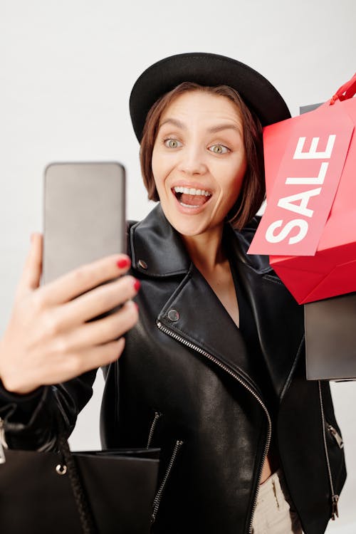 Smiling Woman in Black Leather Jacket Holding Shopping Bags