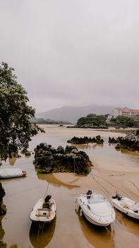 Three boats peacefully docked on the scenic shoreline of Cantabria, Spain.