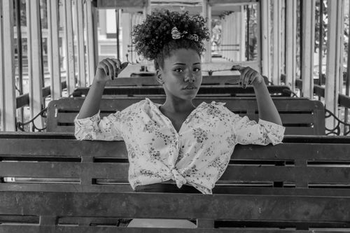 Free Striking black and white portrait of a woman sitting on a bench, showcasing curly hair. Stock Photo