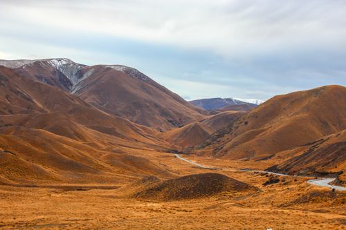 Free Beautiful landscape of brown rolling hills with snow-capped peaks in New Zealand. Stock Photo