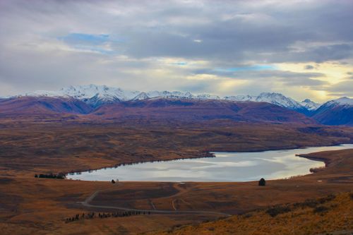 Free Gorgeous view of a serene lake surrounded by snowy mountains under a cloudy sky. Stock Photo