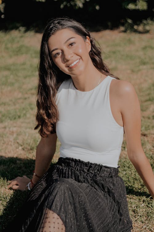 Woman in White Tank Top Sitting on Grass