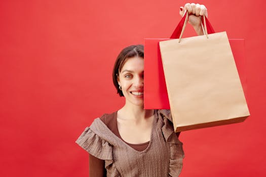 Joyful woman holding shopping bags against a bright red backdrop, expressing excitement.