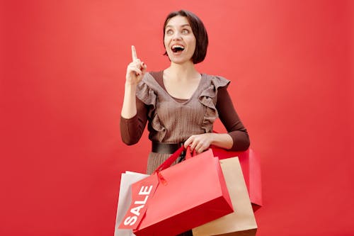 женщина в серой рубашке с круглым вырезом держит красно белую коробку
