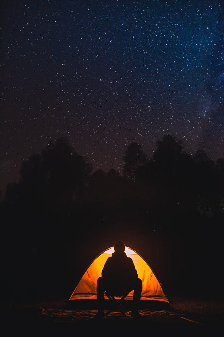 Silhouette Of Person Sitting Beside The Tent