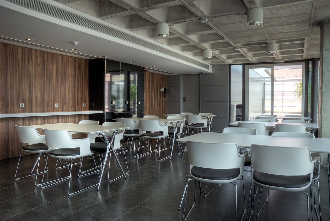 An empty office canteen with rows of tables and chairs. Photo by FROET on Pexels