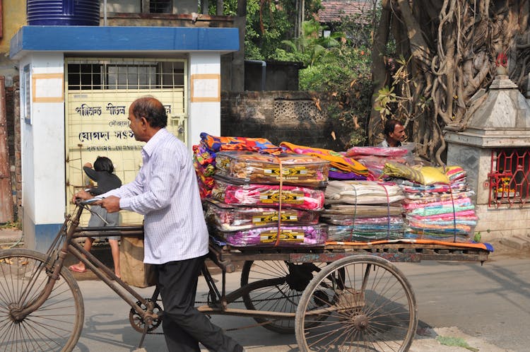 Man Pushing A Tricycle With Blankets