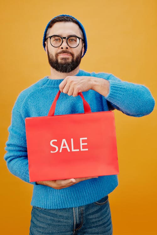 Free Man in Blue Sweater Holding a Red Paper Bag Stock Photo