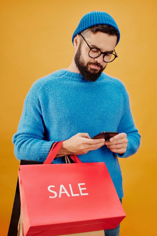 A shopper checking a sale while holding shopping bags