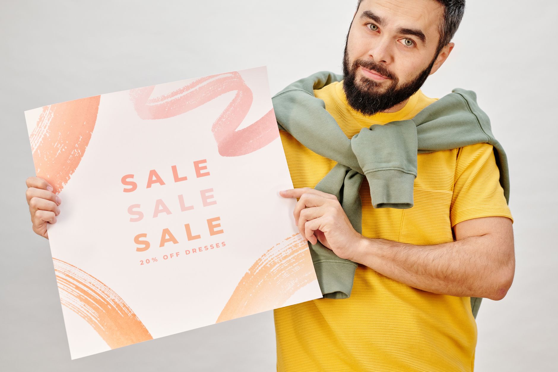 Homme tenant une affiche de promotion annonçant 20% de réduction sur les robes. Parfait pour les promotions du Black Friday.