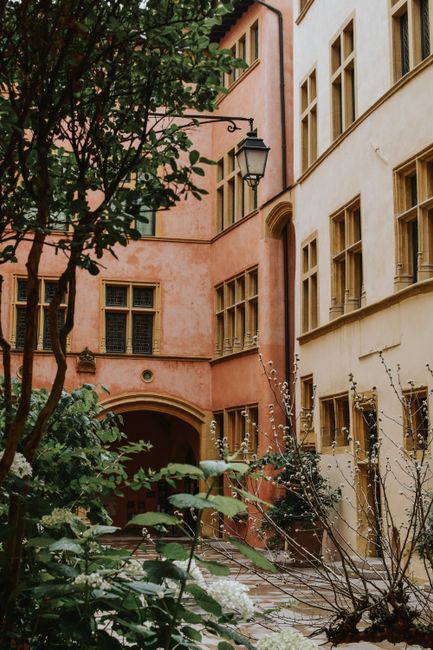 Inner yard of aged simple apartment buildings with arched passage and without balconies on clear summer day